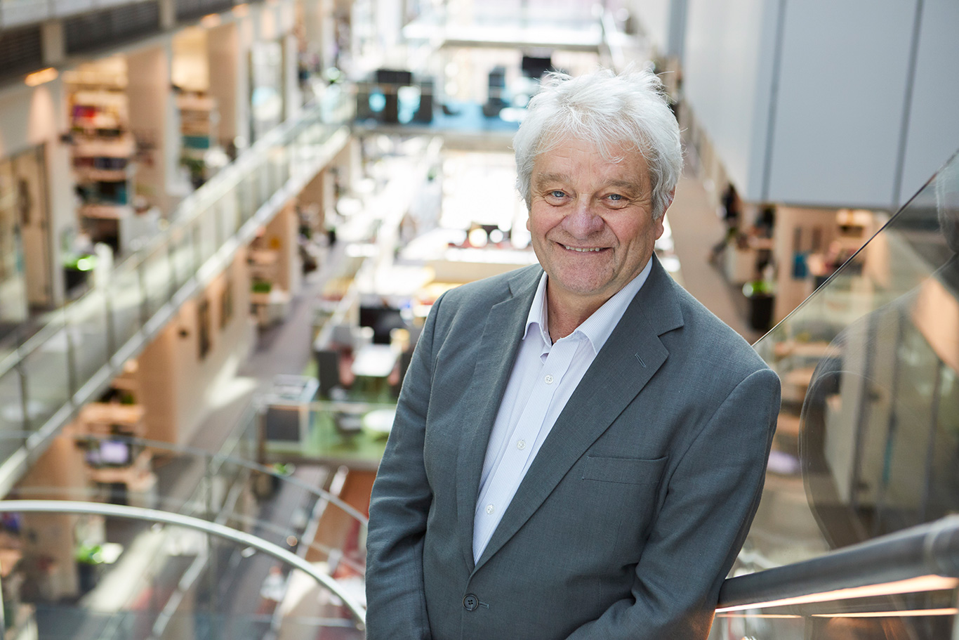 Paul Nurse, gray-haired caucasian male, smiling with a facility in the background